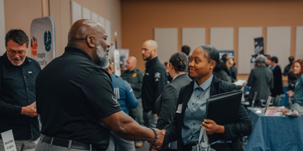 Female student shakes hands with an employer at a job fair. 